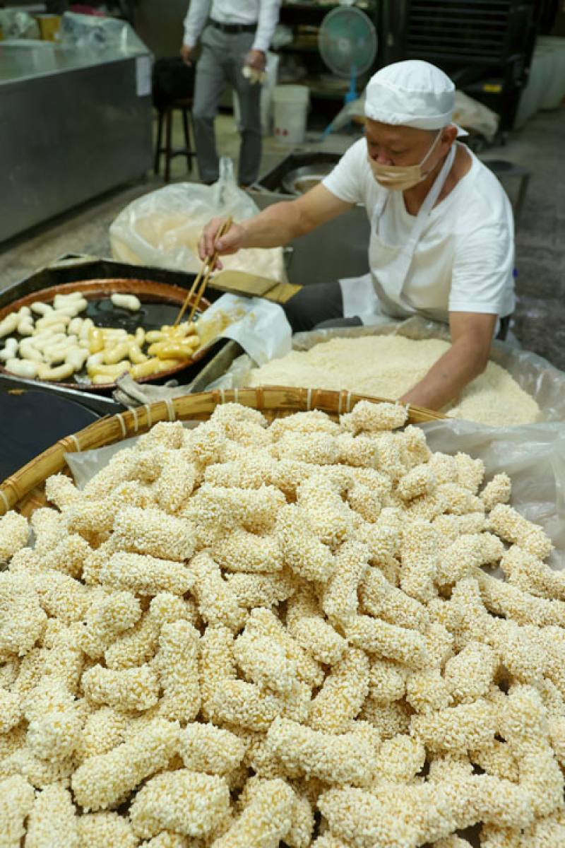 Working alone, a master baker dips lao pastries in maltose syrup, then rolls them in puffed rice. Using both hands, he really looks like a man who has mastered his craft. (photo by Jimmy Lin)
